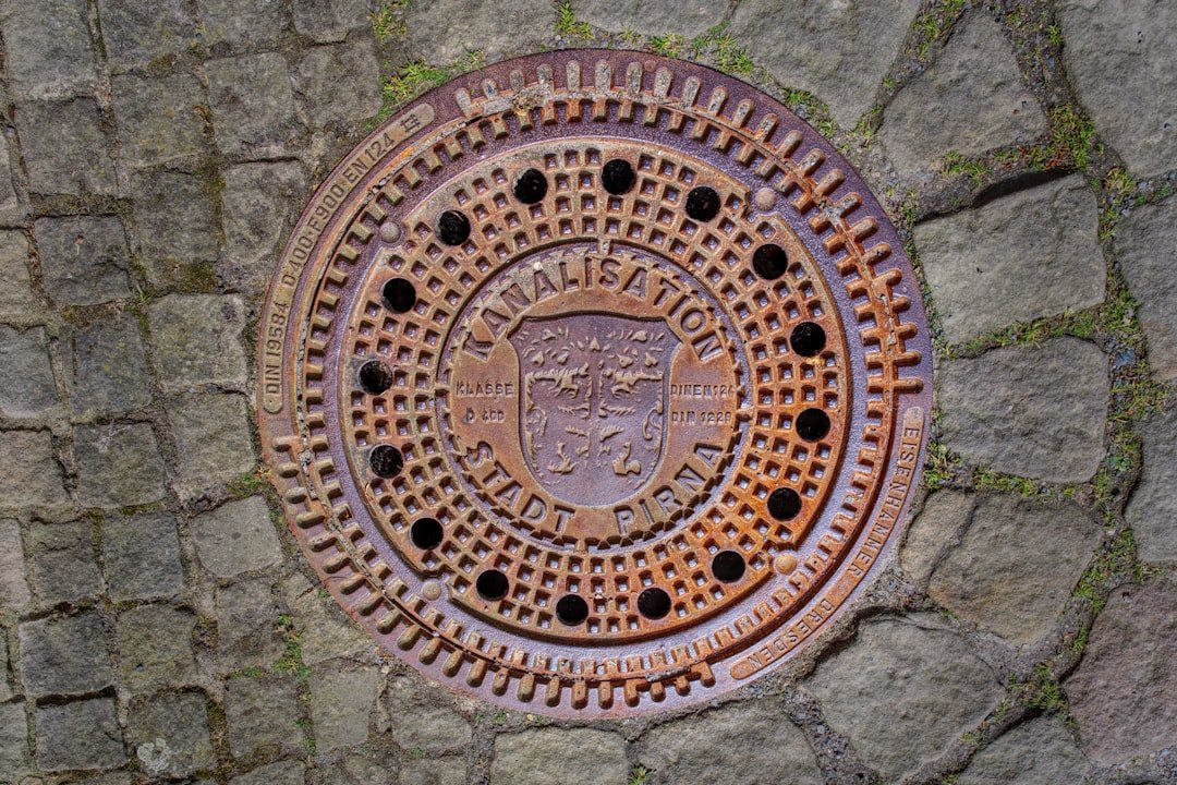 a-rusty-manhole-cover-is-in-the-pavement-oz7d1xjhwjs