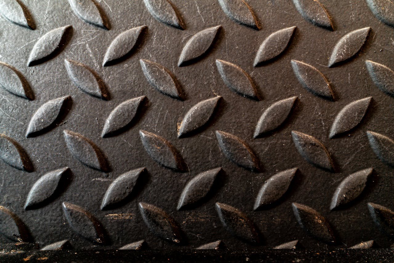 Close-up of a diamond plate metal surface with an oblique textured pattern.