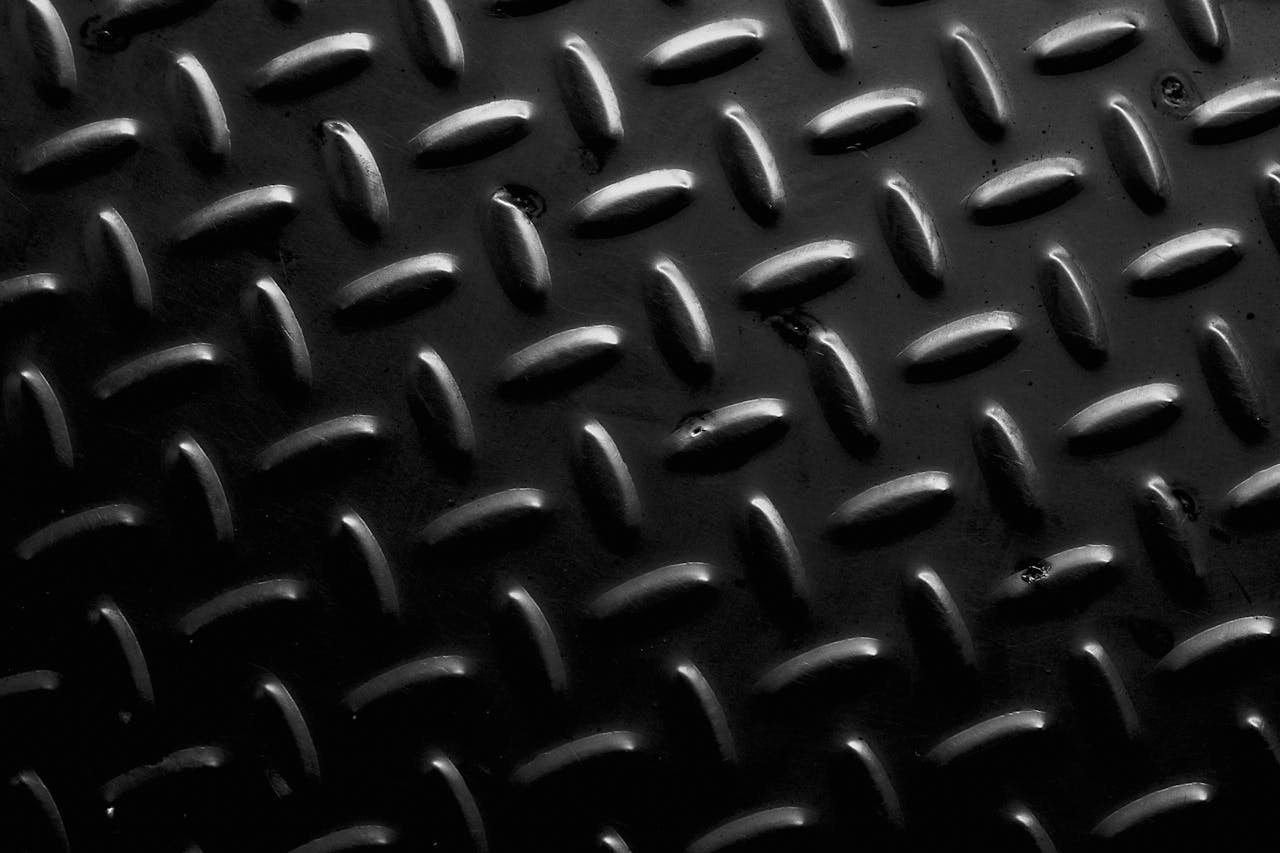 Full frame background with seamless geometric pattern of black metal surface at daylight